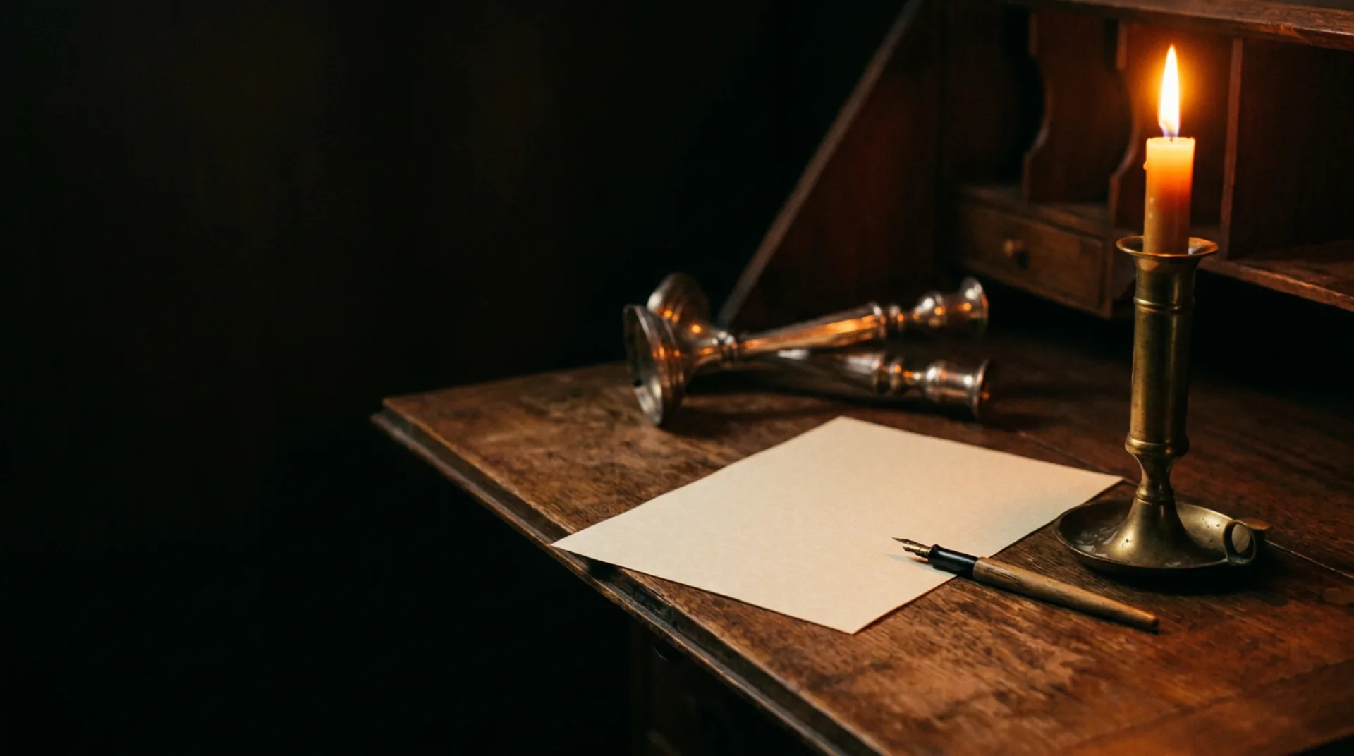 A writing desk with paper, a fountain pen and a lit candle in warm light
